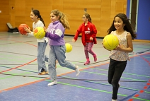 Lachende Mädchen laufen mit Basketbällen durch eine Sporthalle. © Simone Batz, Stadt Marburg